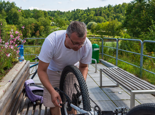 阳光下修理山地自行车的骑行者图片下载