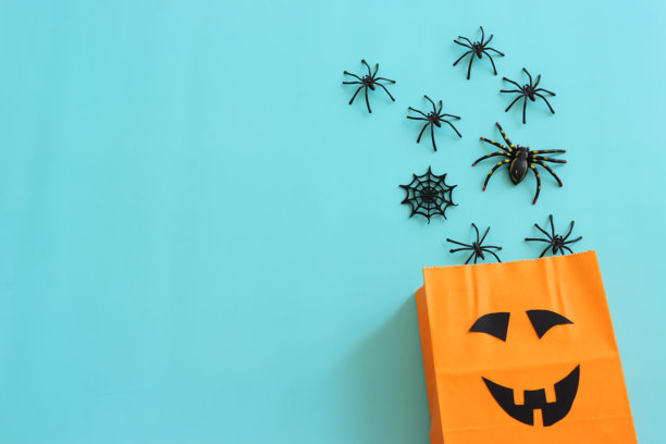 万圣节的假日图片。橙色纸袋，蜘蛛和蝙蝠在蓝色背景上。图片下载