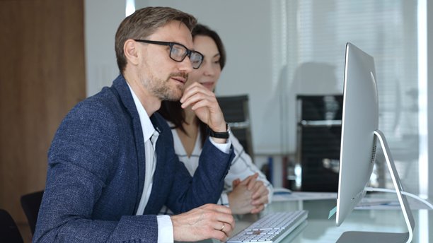 商务人士在办公室会议中，通过电脑屏幕分析金融数据图表，讨论市场研究图片下载