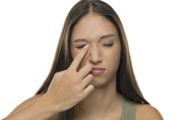 一名年轻女子在白色背景下拍摄的棚拍照片，她留着棕色长发，穿着绿色背心，闭着眼睛抓挠着眼睛。图片下载