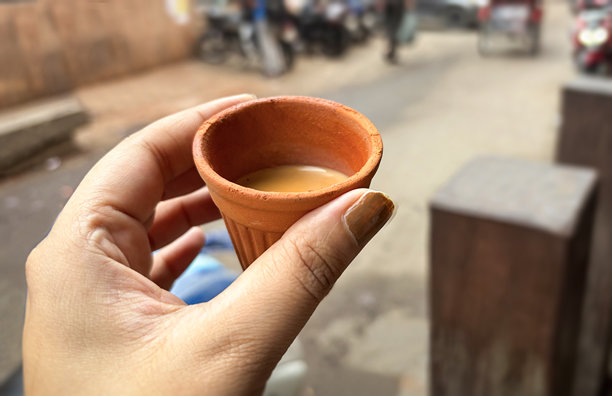 POV特写，手持一个库尔哈德杯（Kulhad cup）的印度香料奶茶（chai）。在街边用库尔哈德杯喝奶茶。图片下载