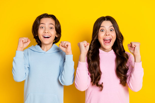 照片肖像，惊叹、惊讶、微笑的孩子们，像赢家一样做出胜利姿势，欣喜若狂，孤立在充满活力的黄色背景上图片下载