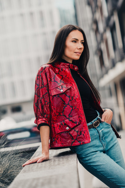 时尚女子身穿红色印花夹克，在阳光明媚的白天享受城市街景，垂直照片图片下载