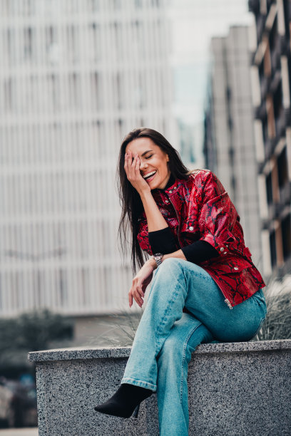 年轻女子身着潮流都市服饰，在休闲的一天里，以城市为背景，享受着欢笑的时刻，竖构图照片图片下载