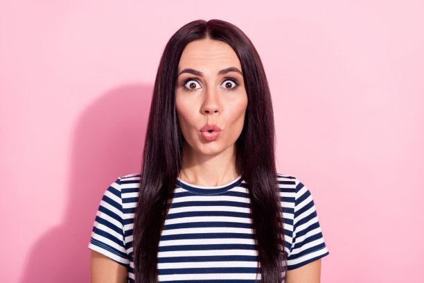 身穿条纹T恤、惊讶、快乐、震惊的年轻女子照片，背景为粉色，孤立图片下载