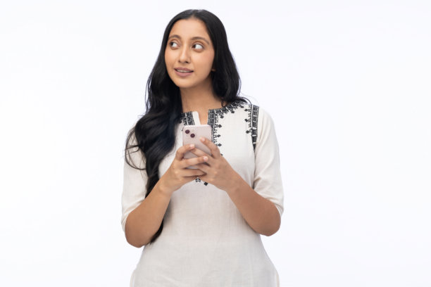 年轻女子身穿白色库尔塔，使用手机，在白色背景下拍摄的照片素材图片图片下载