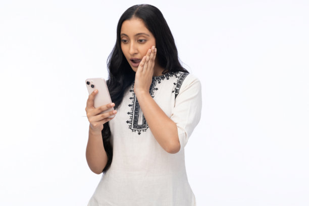 年轻女子身穿白色库尔塔，手持手机，在白色背景下拍摄的肖像照片图片下载