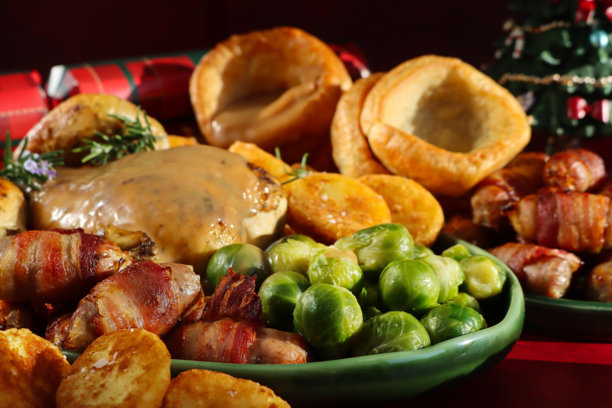 一幅宽幅的圣诞大餐/周日午餐的图片，包含肉汁、鸡肉、抱子甘蓝、烤土豆、约克郡布丁和其他配菜。图片下载