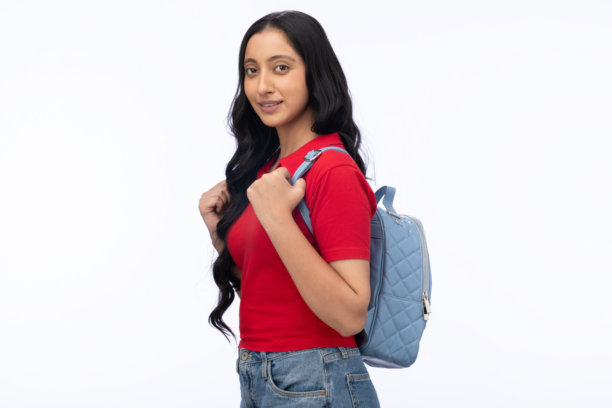 年轻女学生背着包，穿着现代服装，在白色背景下拍摄的独立照片图片下载