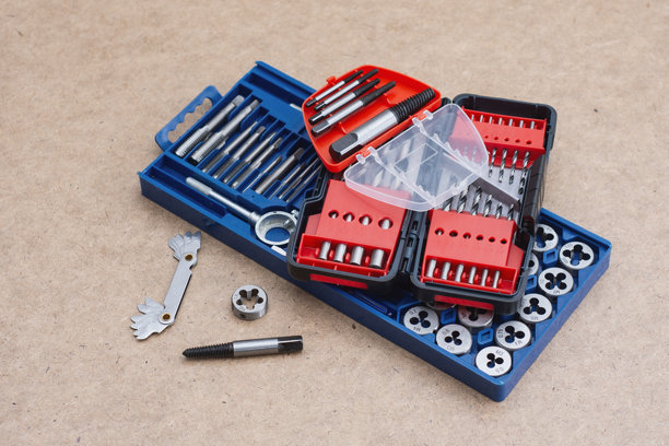 金属丝锥扳手和模具套装，配有手柄、钻头和量规，摆放在木制工作台上。用于金属加工、螺纹加工、维修和工程工作的工业机械师工具。图片下载