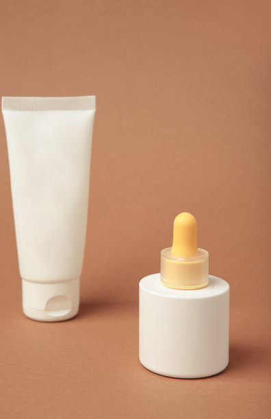 棕色背景上各种空白包装的化妆品，罐子里的面霜，瓶子里的精华液。垂直照片图片下载