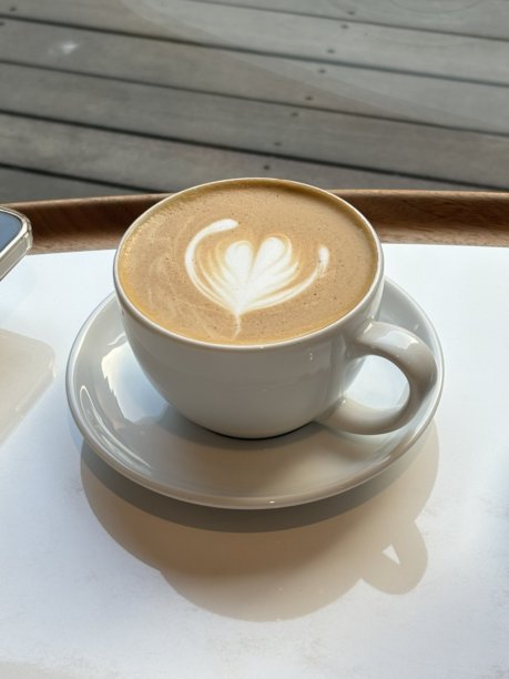 一杯精心制作的拿铁，浓缩咖啡上覆盖着绵密拉花。此图捕捉了经典咖啡馆体验的温暖和诱人特质，非常适合咖啡相关项目图片下载