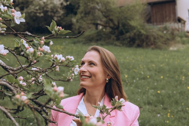 中年女性在春季花园盛开的树旁微笑。寓意女性健康、荷尔蒙平衡、养生和中年自然之美。图片下载