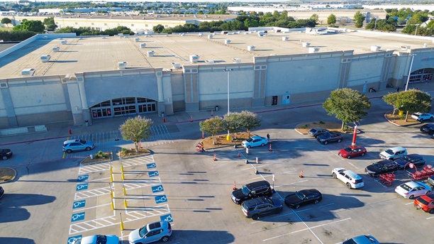 得克萨斯州刘易斯维尔零售商业街的鸟瞰图，包括平顶商店、带遮阳的停车场以及旁边的仓库建筑。树木、区域规划对比和消费者流动定义了这条混合用途的走廊。图片下载