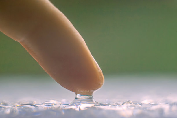 特写照片，手指触碰桌上的水滴图片下载
