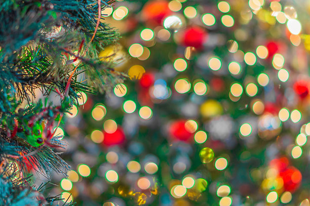 一张模糊失焦的照片，拍摄的是装饰有彩灯和花环的圣诞树或新年树，彩灯闪烁发光，营造出散景效果。背景拍摄，失焦。图片下载