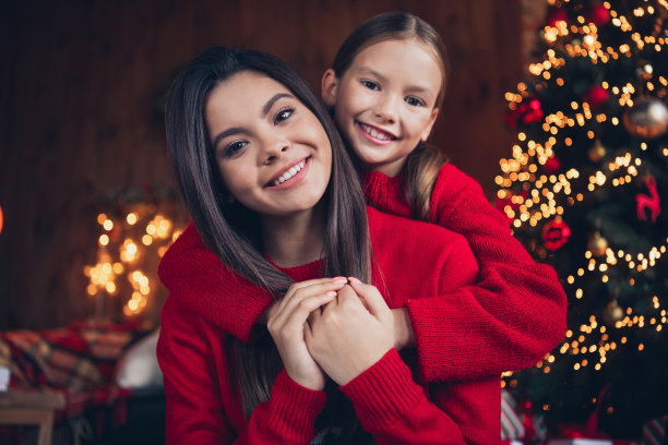 照片：穿着红色毛衣的快乐积极的小兄妹俩在圣诞公寓家中依偎在一起玩耍图片下载