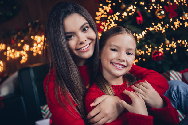 照片：穿着红色毛衣的闪亮可爱小兄妹，在室内的圣诞公寓家中依偎在一起，面带微笑。图片下载