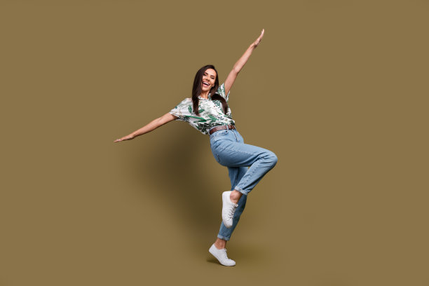 棕色背景下，一名欣喜满意的年轻人在全长照片中举起双手，尽情舞动，姿态放松，画面隔离。图片下载