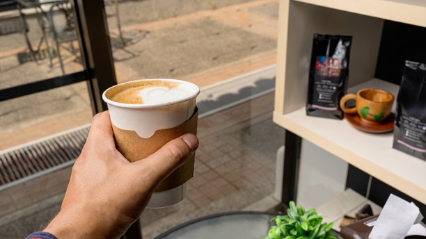 手持带有心形拉花图案的咖啡拿铁图片下载