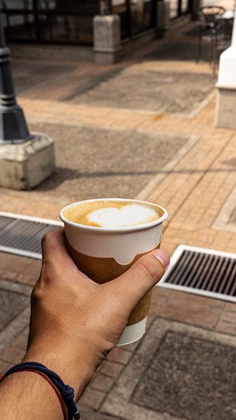 街头手持带有拉花艺术的咖啡杯图片下载