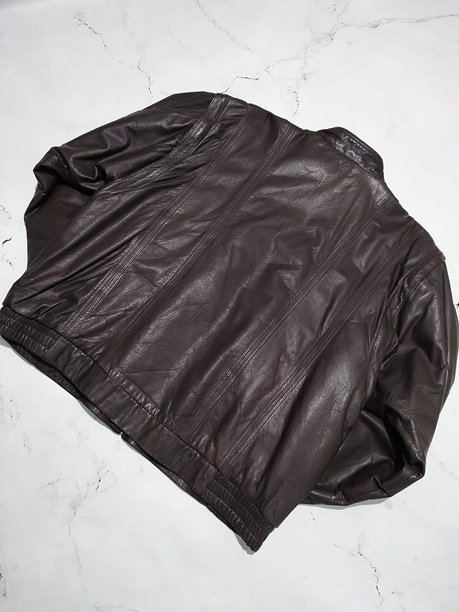 棕色真皮男士飞行员夹克平铺俯视图，孤立在灰色大理石背景背面。Y2K复古外套，时尚。保暖的夹克，适合冬季。光泽的真皮纹理。图片下载