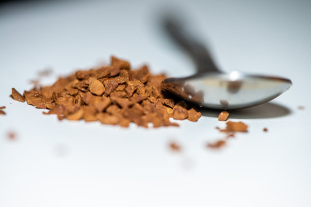 白色背景下，勺子装满咖啡豆的微距照片图片下载