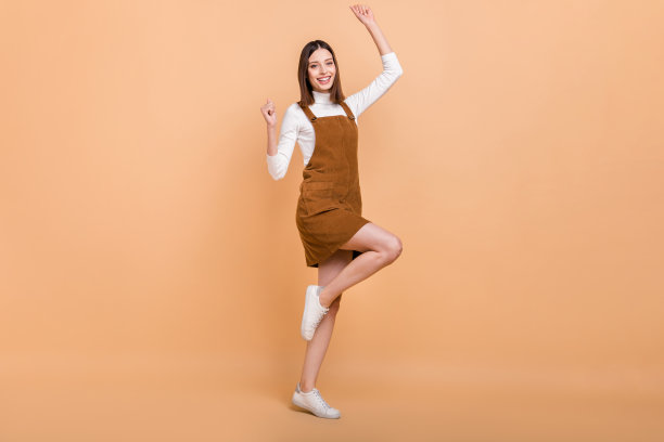 一名兴高采烈、笑容灿烂的人士，双手握拳，幸运地高举双臂，独立于米色背景，全景照片。图片下载