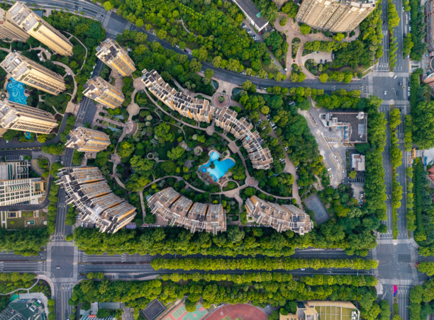 俯瞰照片展示了人口稠密的居民区，其间点缀着现代建筑，四周环绕着茂密的绿植。图片下载