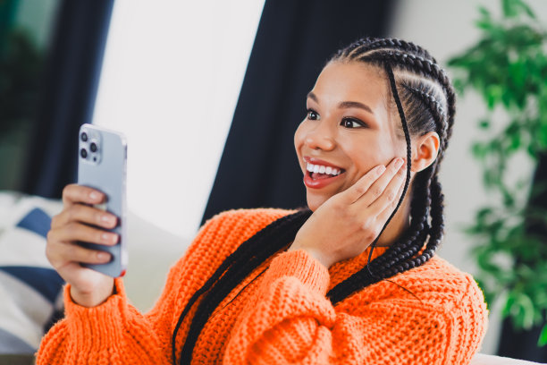 一位女士在家中，穿着橘色针织毛衣，在明亮的客厅里自拍，用于生活方式类图库照片图片下载