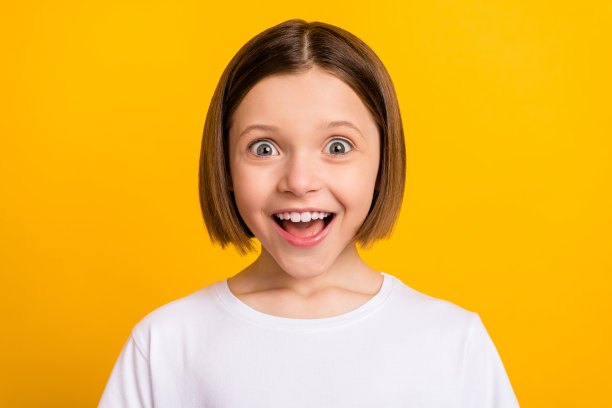 照片肖像：留着波波头的小女孩，惊讶地张着嘴，欣喜若狂，背景是鲜艳的黄色图片下载