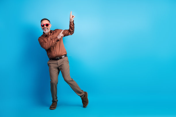 身穿时尚棕色衬衫的商人在明亮的蓝色背景前跳舞，用于企业营销照片拍摄图片下载