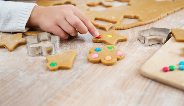 特写：孩子用饼干模具从生面团中切割圣诞饼干。概念：家庭传统和圣诞节假日的准备。图片下载