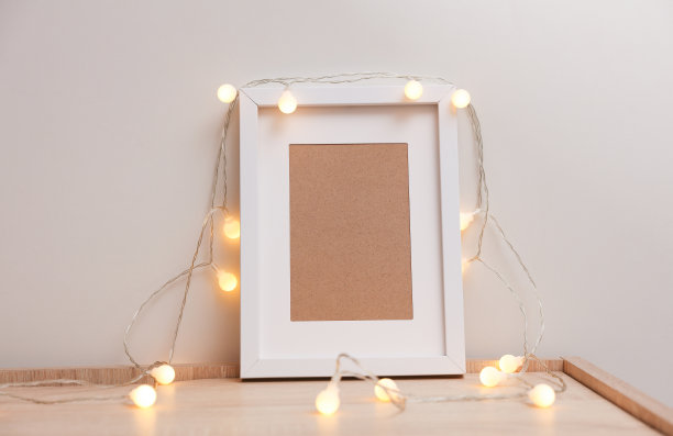 抽屉柜上摆放着空白相框和白色LED灯串，用于设计素材展示。图片下载