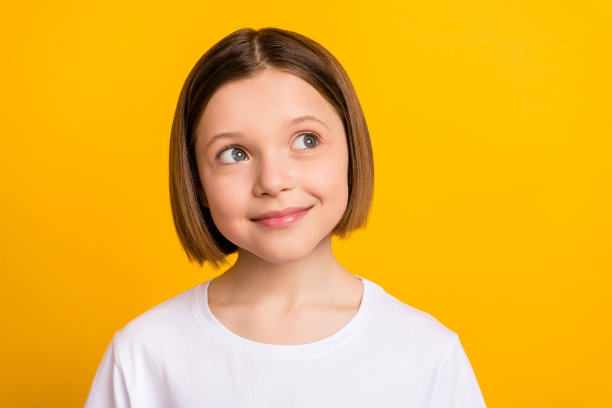 照片肖像：留着波波头的可爱小女孩，好奇地看向镜头，背景为充满活力的黄色，有留白 copyspace图片下载