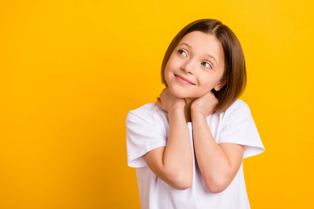 照片肖像，可爱的小学女生，面带灿烂的微笑，表情愉悦，孤立在明亮的黄色背景前，留有空白空间图片下载