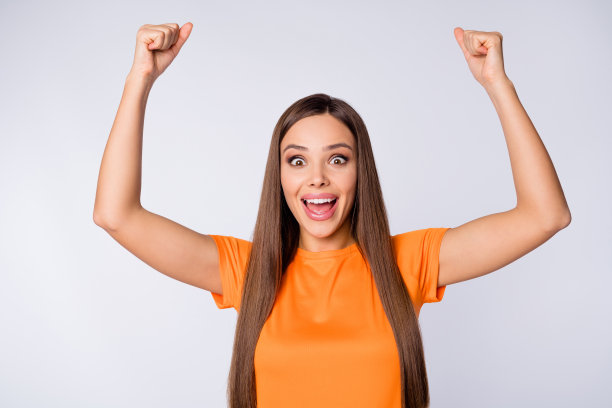 特写照片：疯狂喜悦的女球迷，身穿橙色国家队足球队服，高举双臂挥舞拳头，为欧洲杯联赛的足球队加油助威，背景为纯白色。图片下载