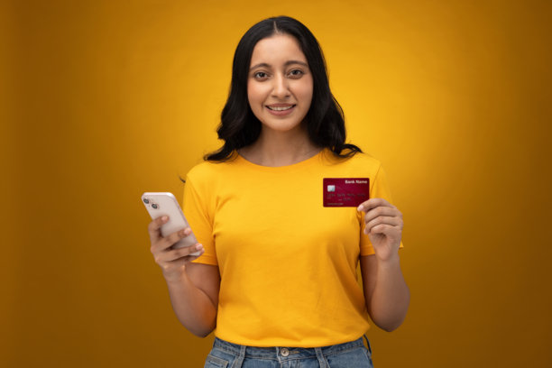 身穿黄色T恤的年轻女子在线购物，孤立在黄色背景上的照片素材照片图片下载