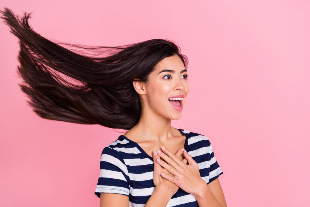 印象深刻的年轻千禧一代女士的个人资料照片，她穿着条纹T恤，望向空白处，背景是粉彩色调的粉色。图片下载