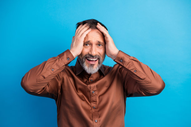 自信的成熟商人，身穿棕色衬衫，在蓝色背景下因压力而托着头，构成富有动感的图库照片概念。图片下载