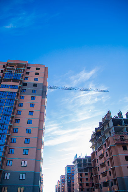 一张描绘新建住宅楼施工的垂直照片，背景中有一台起重机，在充满活力的氛围中突显了城市发展和建筑创新的动态，体现了公寓综合体、多层住宅的概念。图片下载