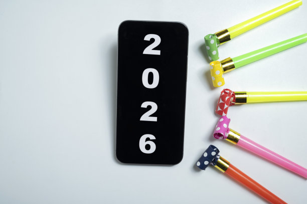 手机屏幕上带有“2026”字样的日历，旁边是派对喇叭。包含样机或复制空间。新年快乐概念或庆祝活动。图片下载