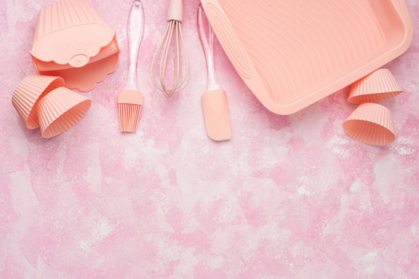 粉色墙壁背景上的杯子蛋糕硅胶模具和粉色烘焙用具图片下载