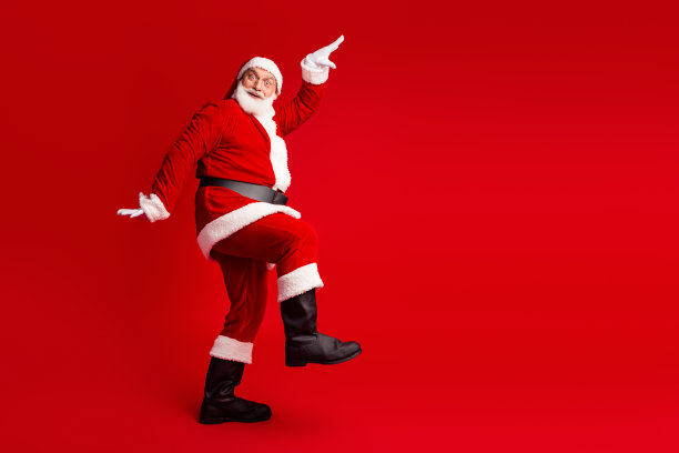 身穿红色圣诞老人服装的人物，在明亮的红色背景前快乐地踢腿，营造出节日的圣诞氛围，适合用作素材图片。图片下载