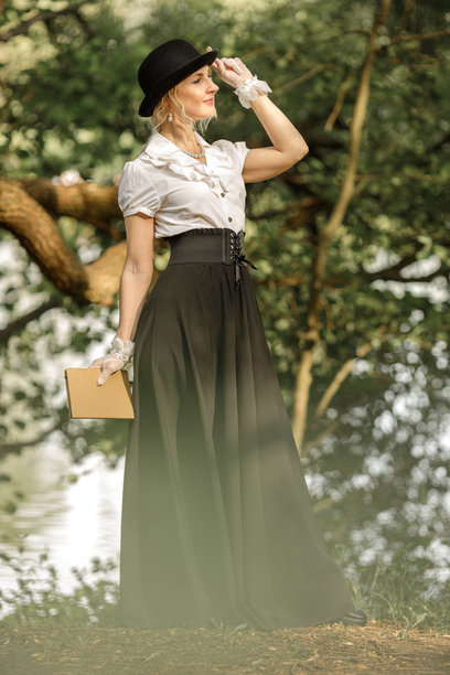 森林中身着维多利亚时代服饰的金发美女手捧书籍，复古风格图片下载