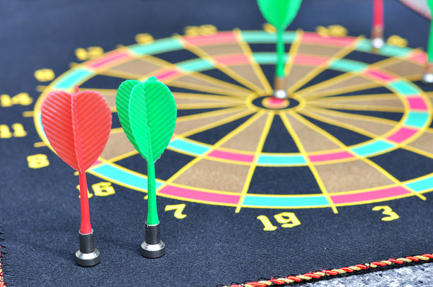 飞镖盘上的红色和绿色飞镖。竞争和目标实现的理念。图片下载