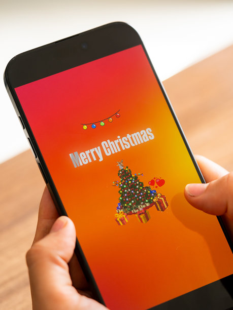 圣诞节和新年庆祝活动照片。垂直照片，以圣诞树枝、铃铛、美好祝愿和字体设计为特色。用于广告、封面和社交媒体的极简新年手册。图片下载