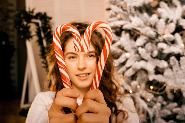 一位美丽的卷发女孩站在树旁，拍摄新年棒棒糖照片图片下载