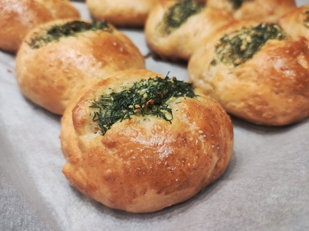 烤盘上新鲜出炉、热气腾腾的蒜香香草面包特写。自制烘焙照片。图片下载