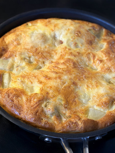 一张健康的早餐图片，展示了一个富含蛋白质的鸡蛋意式烘蛋（或煎蛋卷），配有土豆和洋葱，正在不粘锅中烹饪。图片下载